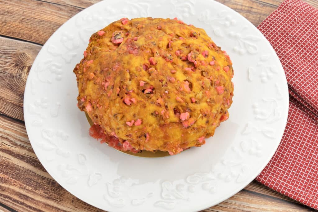 Brioche aux pralines roses sur assiette blanche décorée, posée sur une table en bois avec une serviette rouge.